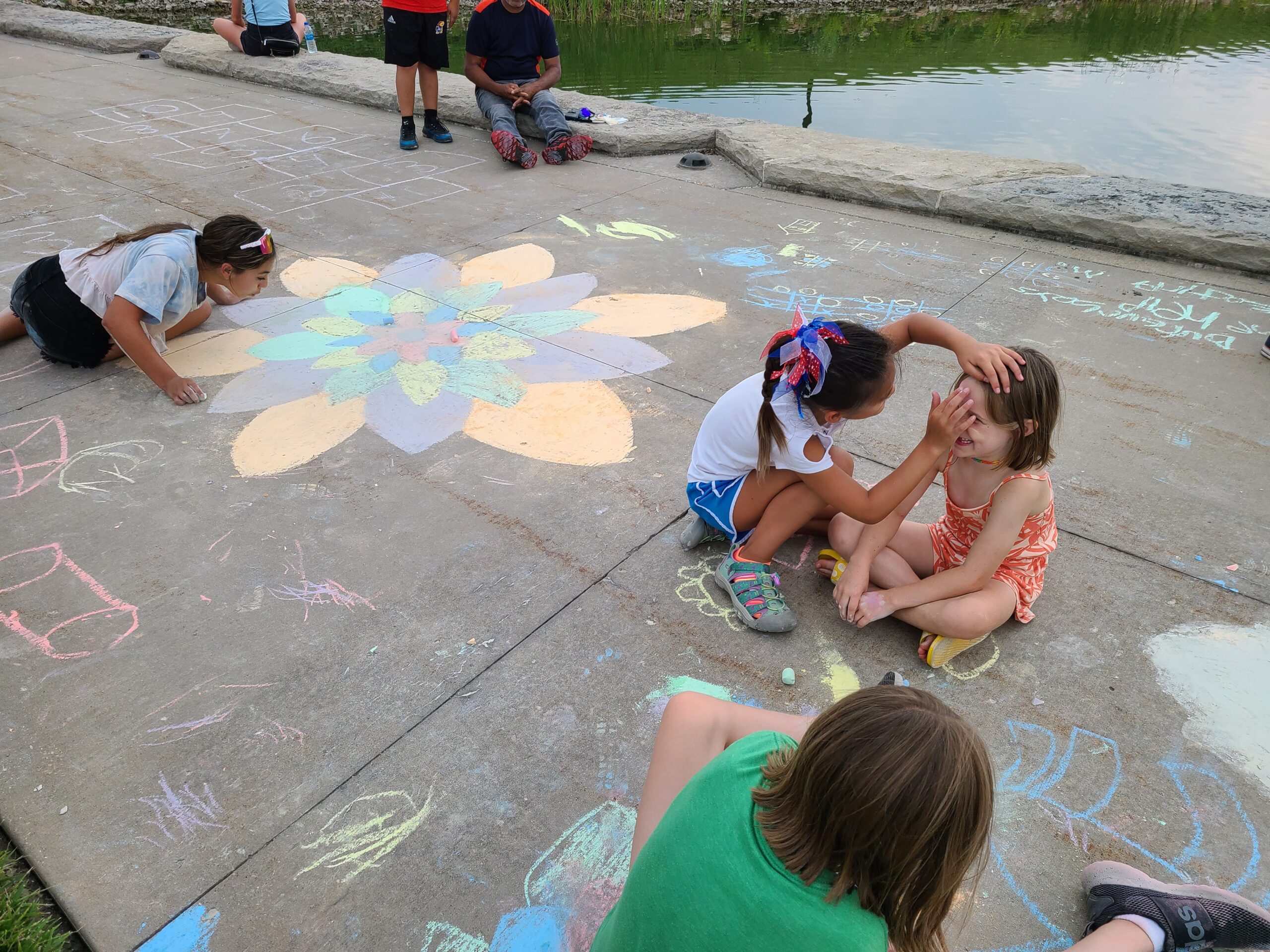 Children decorating the sidewalk outside the Dole Institute with chalk drawings