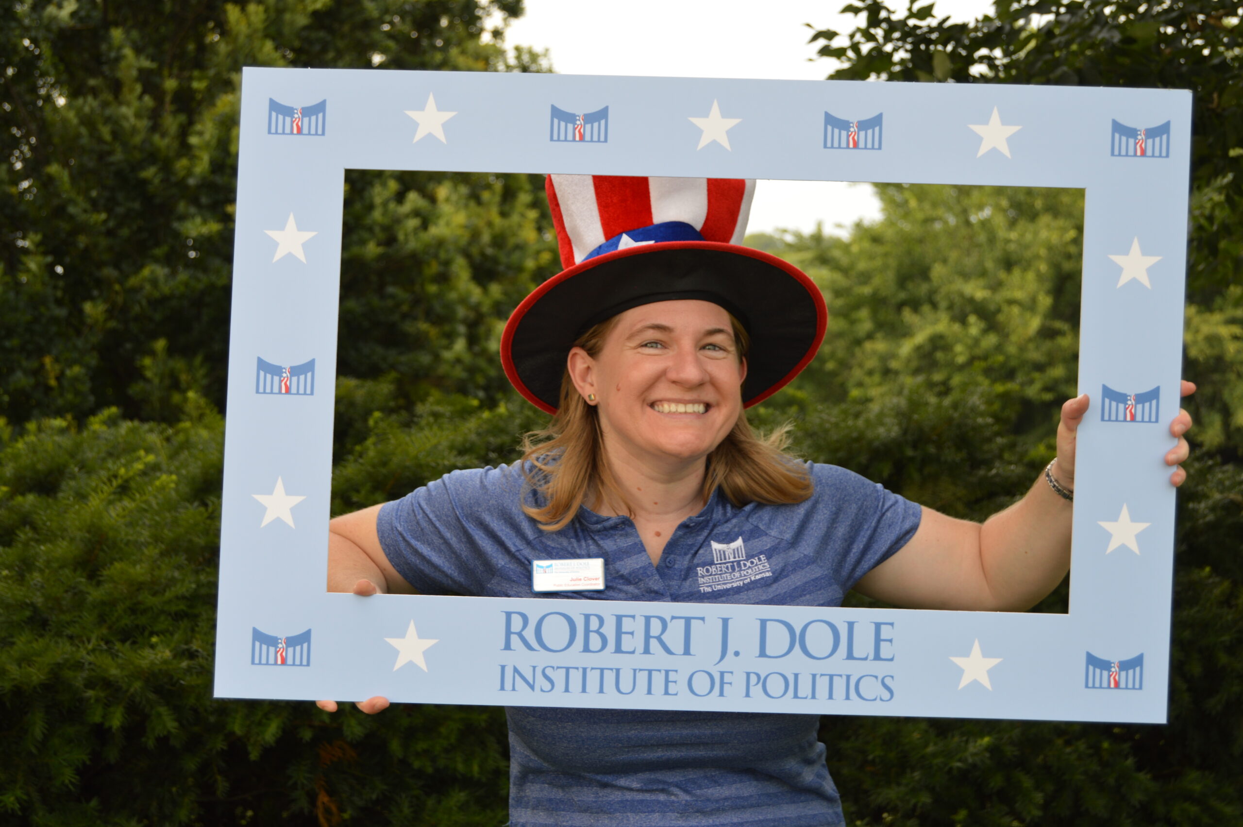 Julie Clover with an uncle sam hat, holding a frame around her face that reads 'Robert J. Dole Institute of Politics'