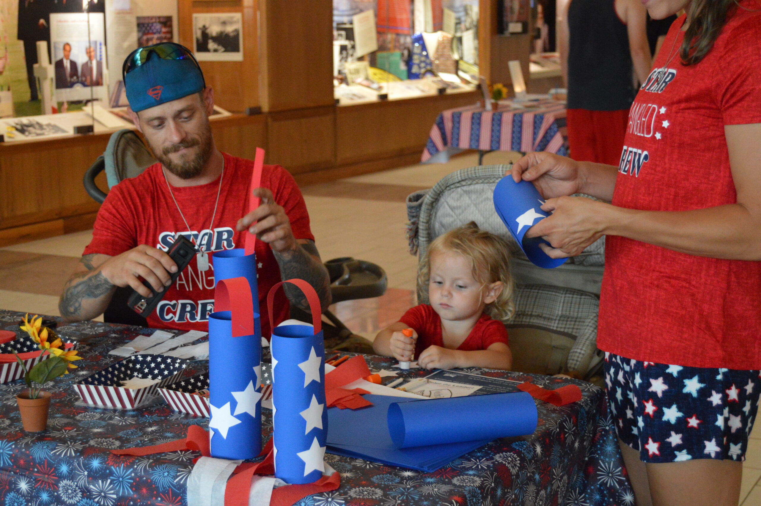 Parents and children crafting Patriotic Red, White, and Blue Windsocks inside the Dole Institute