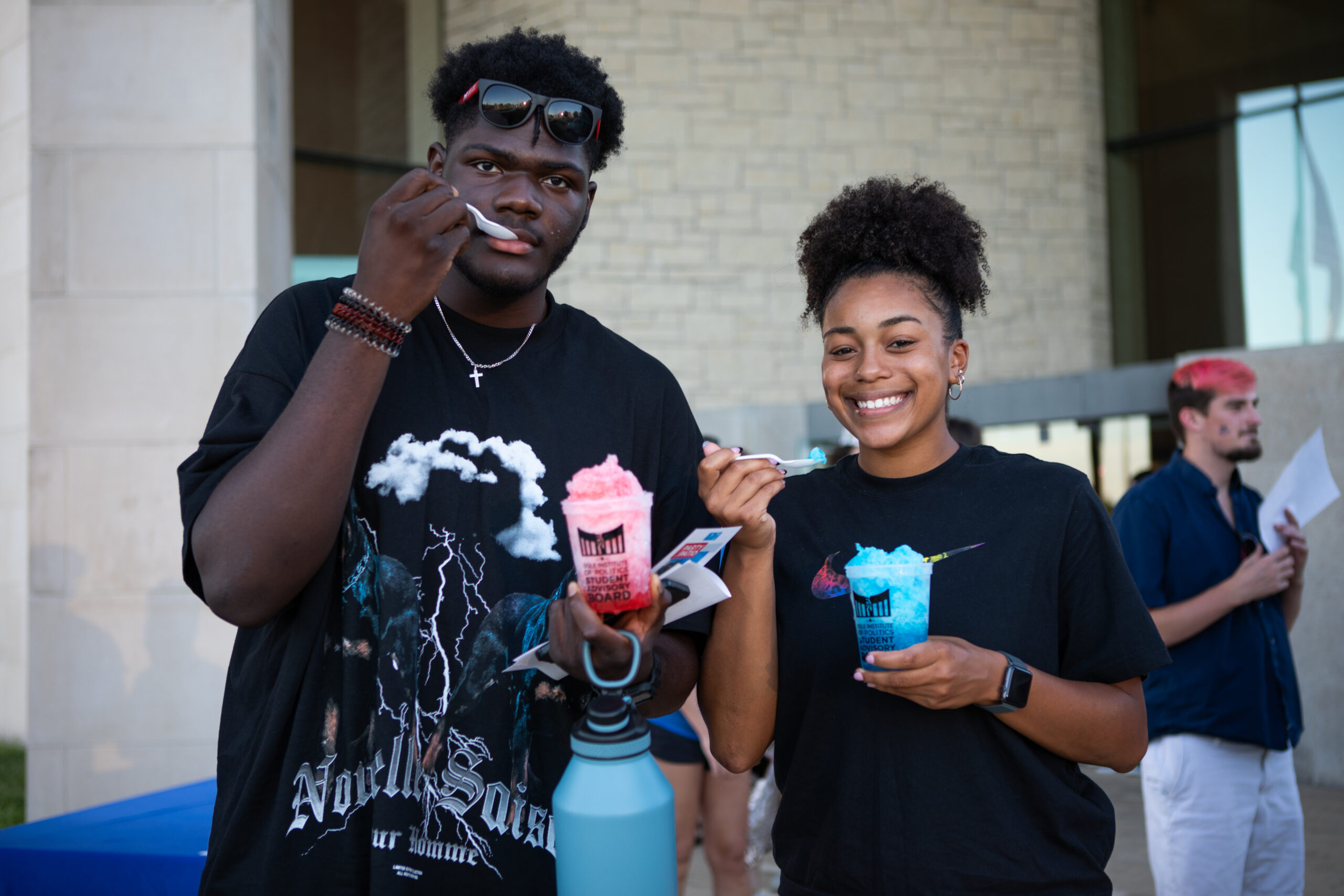 two students holding cups of shaved ice outside the Dole Institute