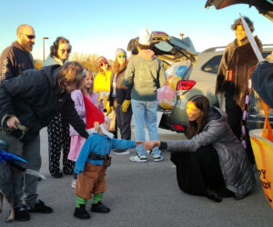 A KU student hands a piece of candy to a child dressed as a gnome at the KUCCO Trunk-or-Treat event on October 30, 2023.