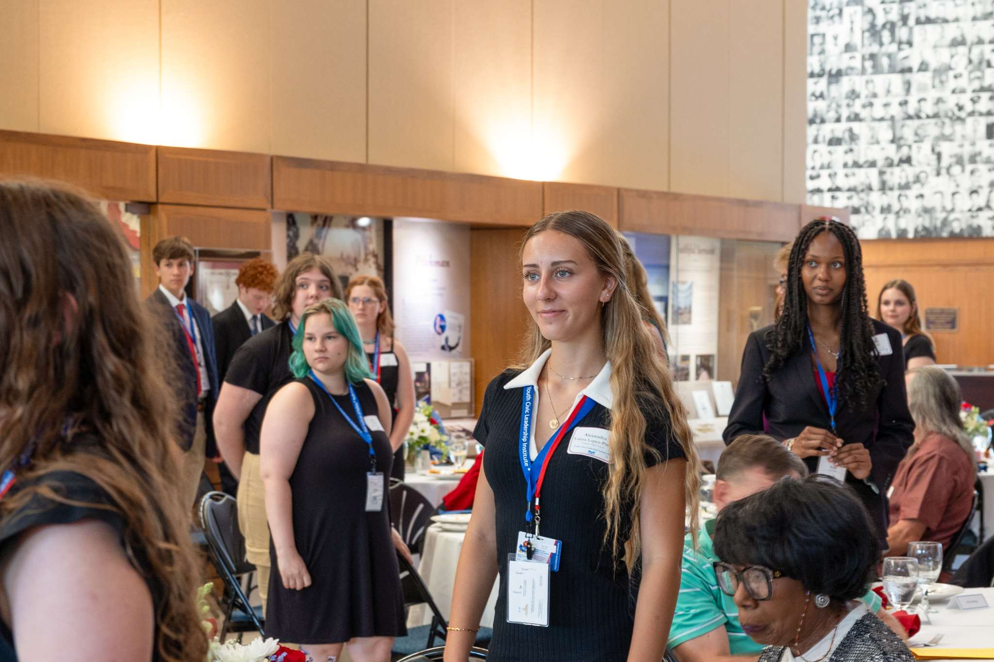 A young woman smiles while she and others in the background look on.