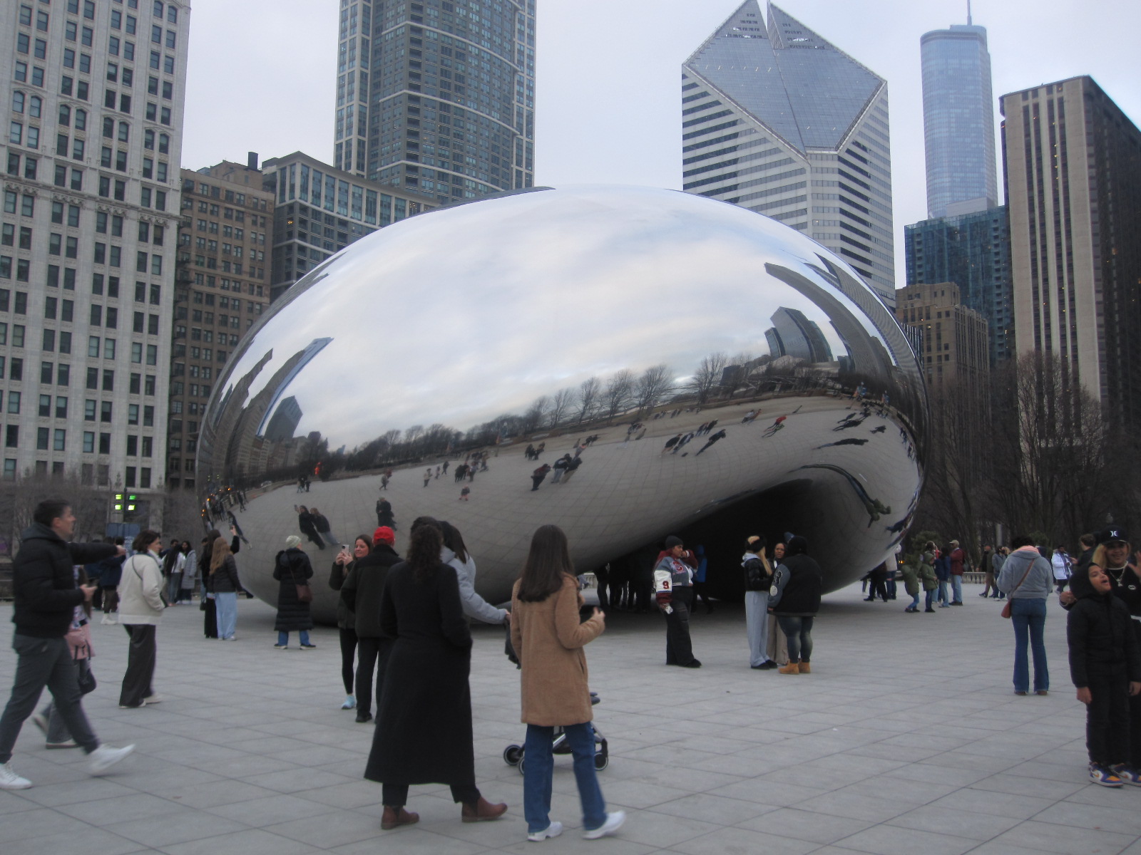 People view a giant chrome sculpture in a park.